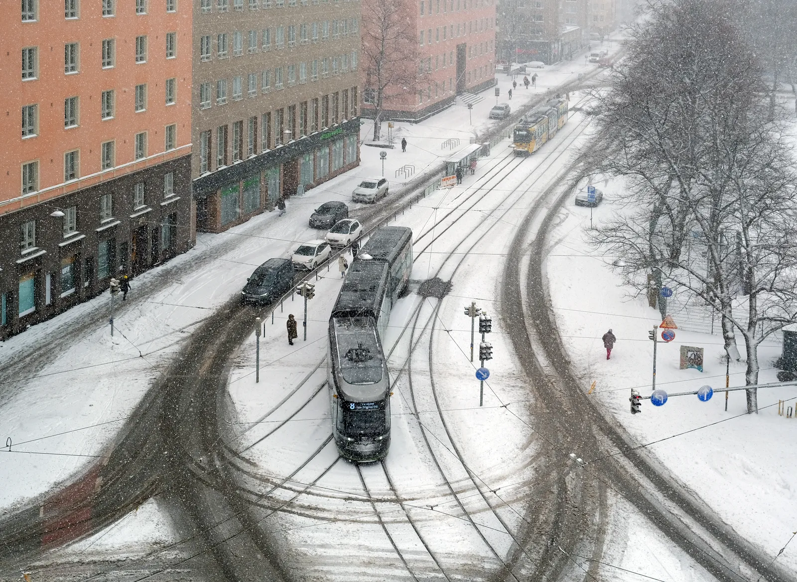 Trams and pedestrians on snow-covered Helsinginkatu in Helsinki